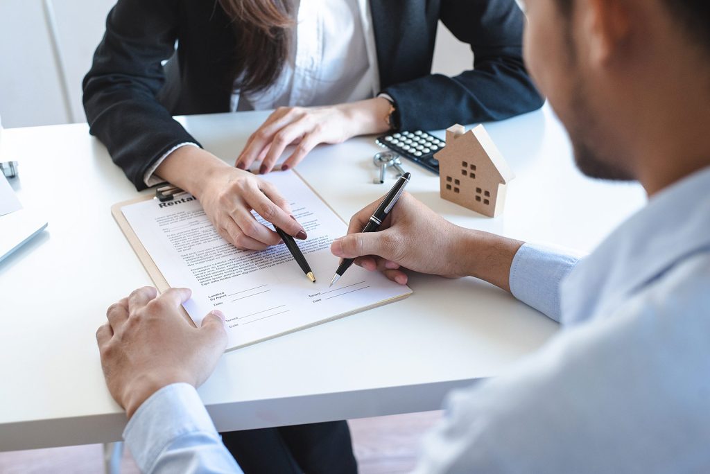 Hombre firma un contrato donde le indica una mujer de traje